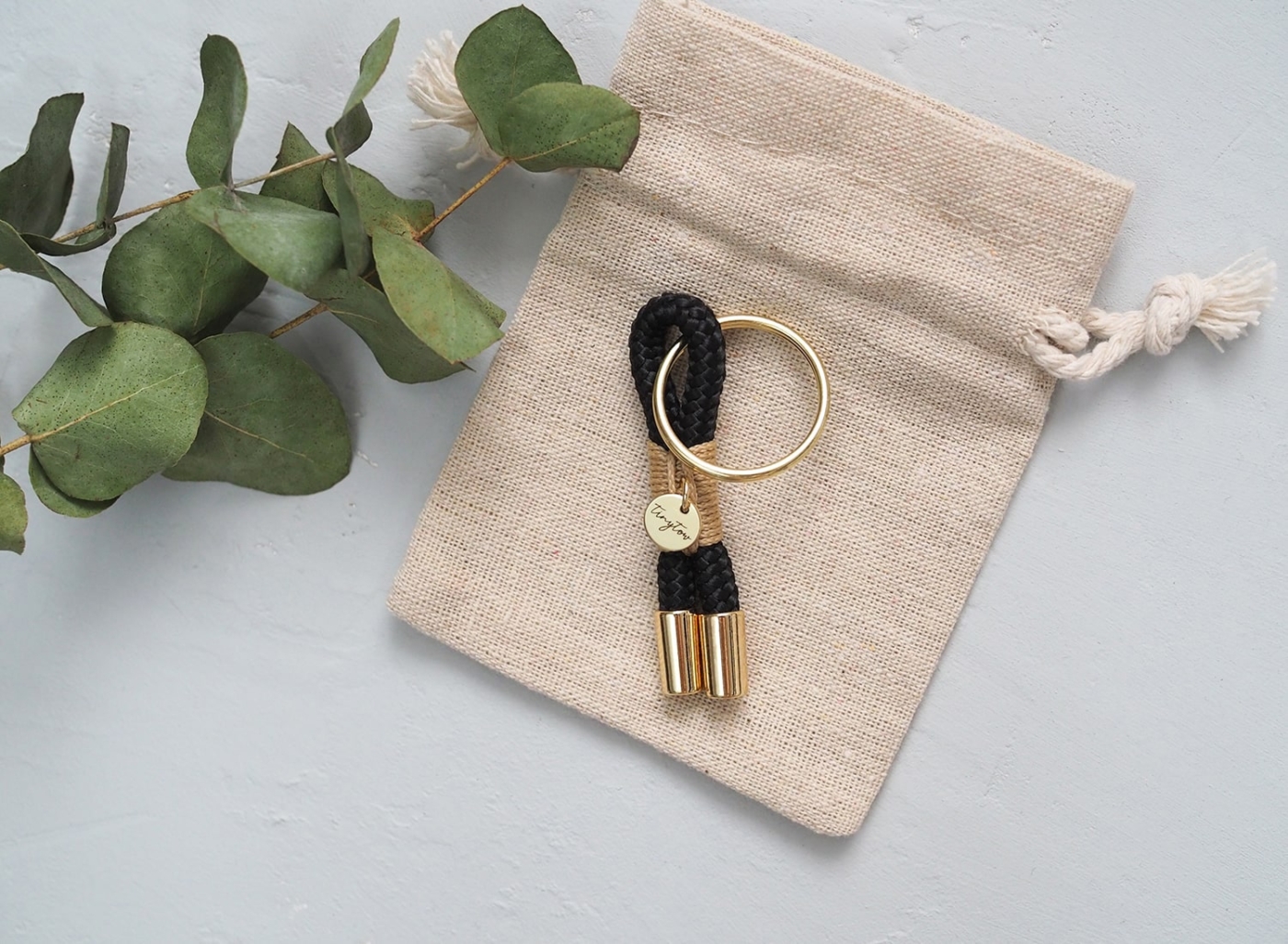 Schlüsselanhänger aus Tau in schwarz beige mit goldenen Details.