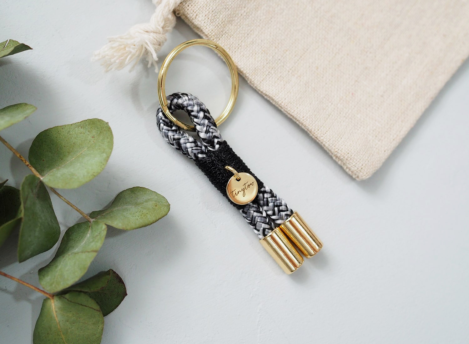 Schlüsselanhänger Towy mit schwarz-weißem Tauseil, schwarzer Takelung und goldenen Details.