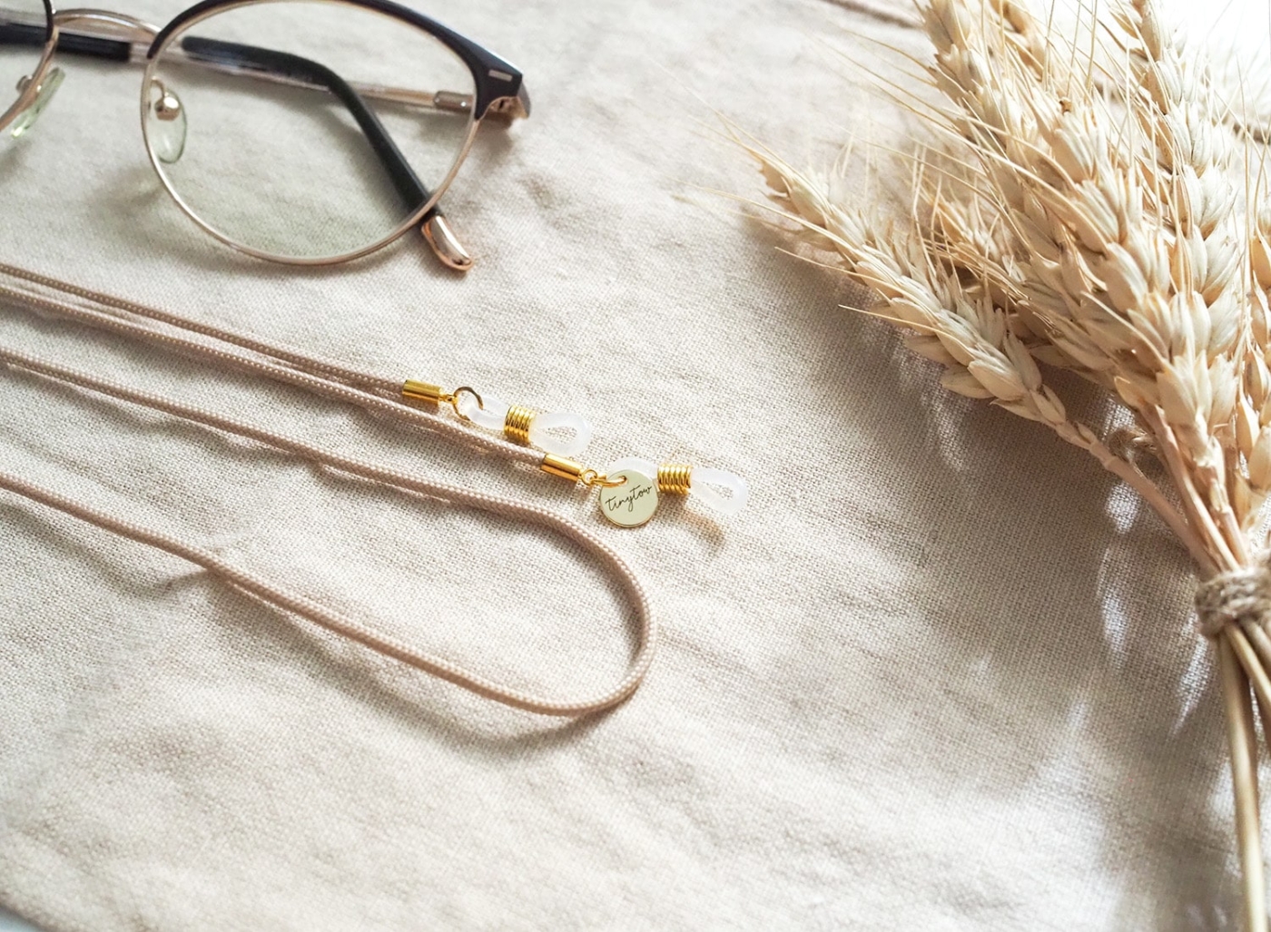 Brillenband in beige mit goldenen Details.
