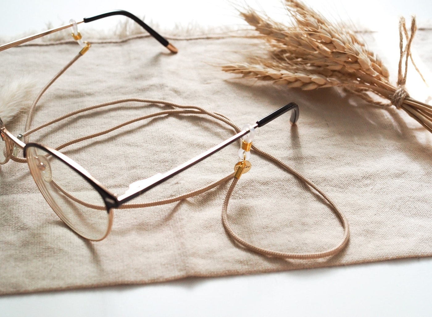 Brillenband in beige mit goldenen Details an Brille.