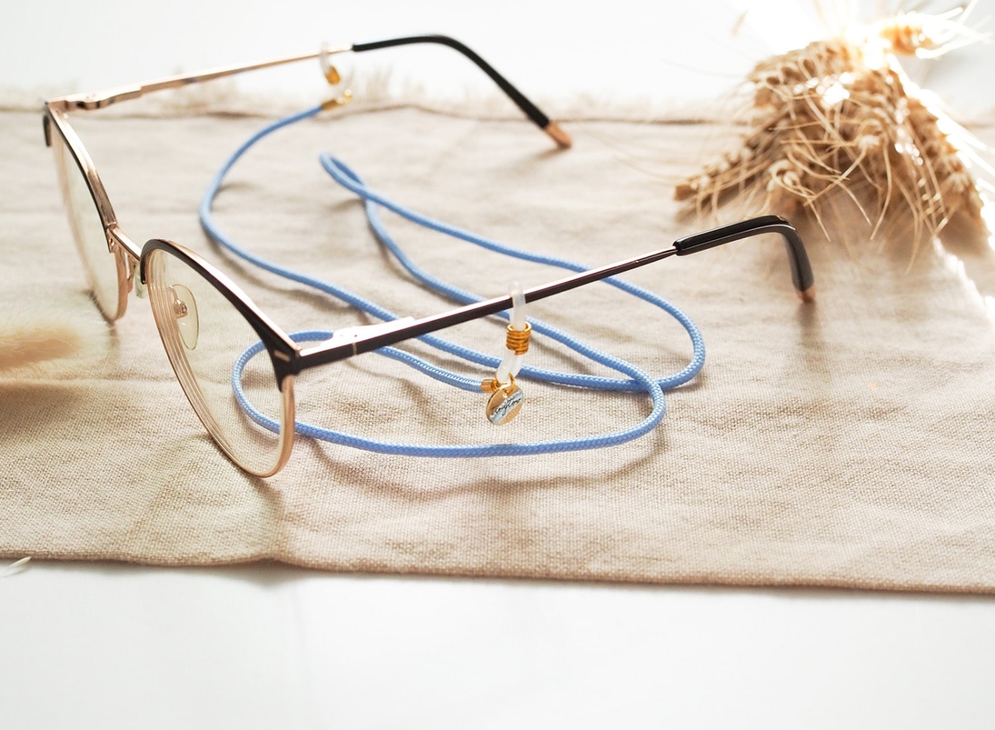 Brillenband hellblau mit goldenen Details und Silikonschlaufen an Brille.